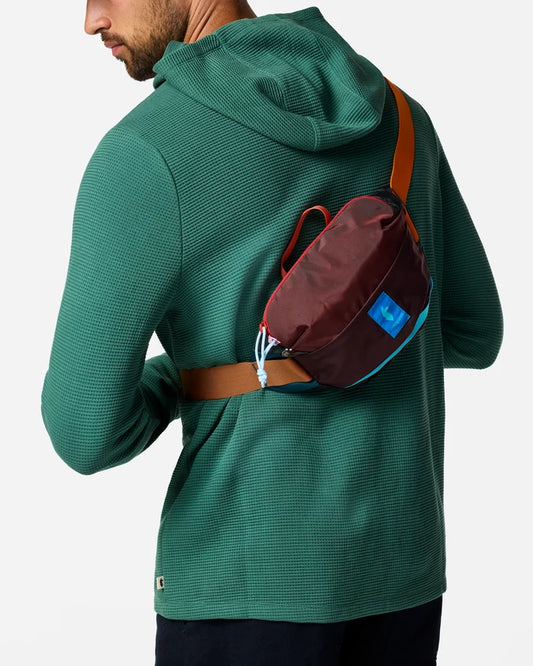 A man with a green hoodie wearing a sling bag across his back