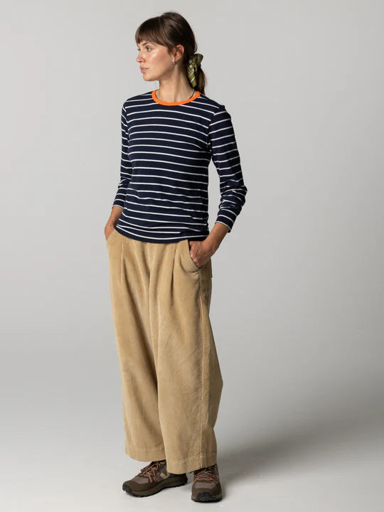 Person wearing a striped long-sleeve shirt and beige pants on a plain background