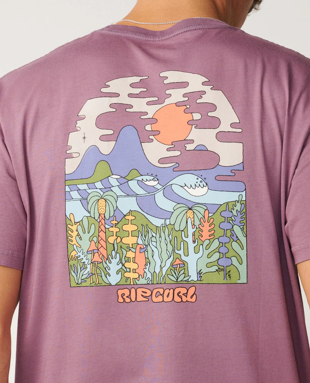 Purple t-shirt with a colorful graphic design on the back, featuring mountains, a sun, and plants, with 'Rip Curl' branding.