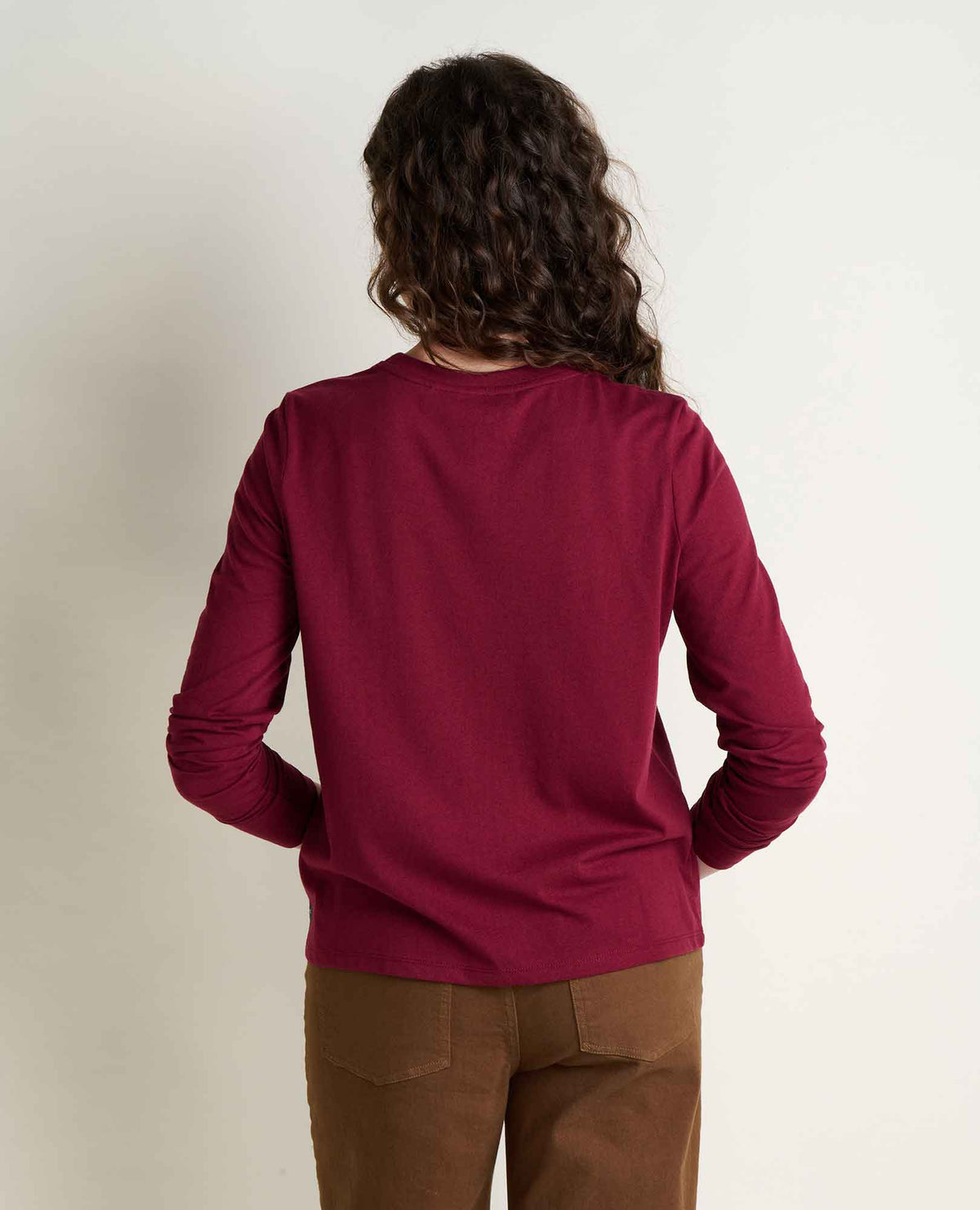toad and co re form long sleeve crew back view of woman wearing burgundy long sleeve shirt with tan pants 2 pockets