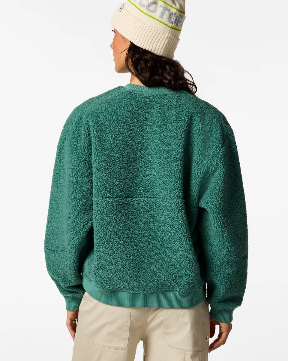 The back view of a woman wearing an Amigazo Fleece from Cotopaxi with a cream hat and cream pants