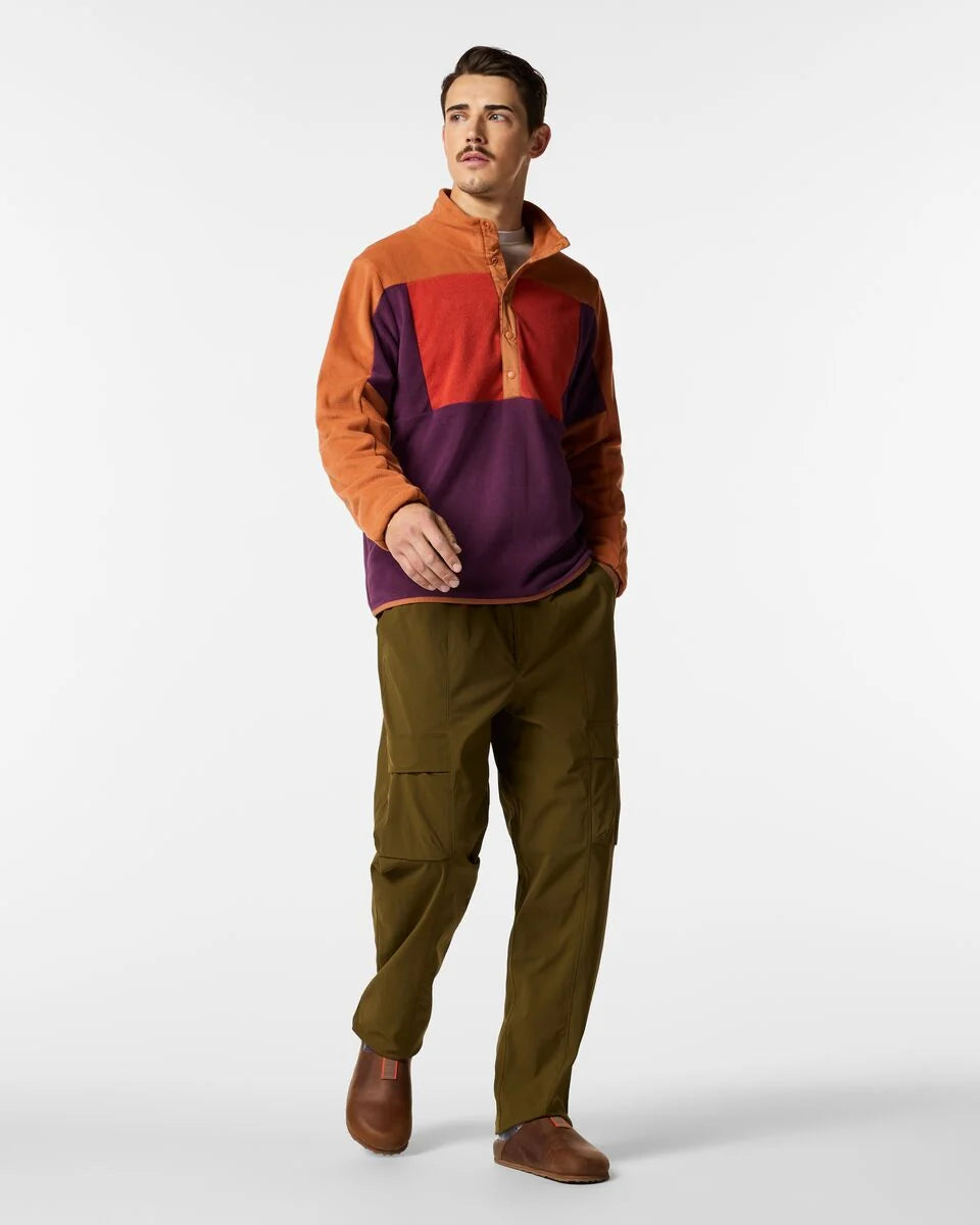 Man wears green pants and bright colour blocked fleece pullover with buttons