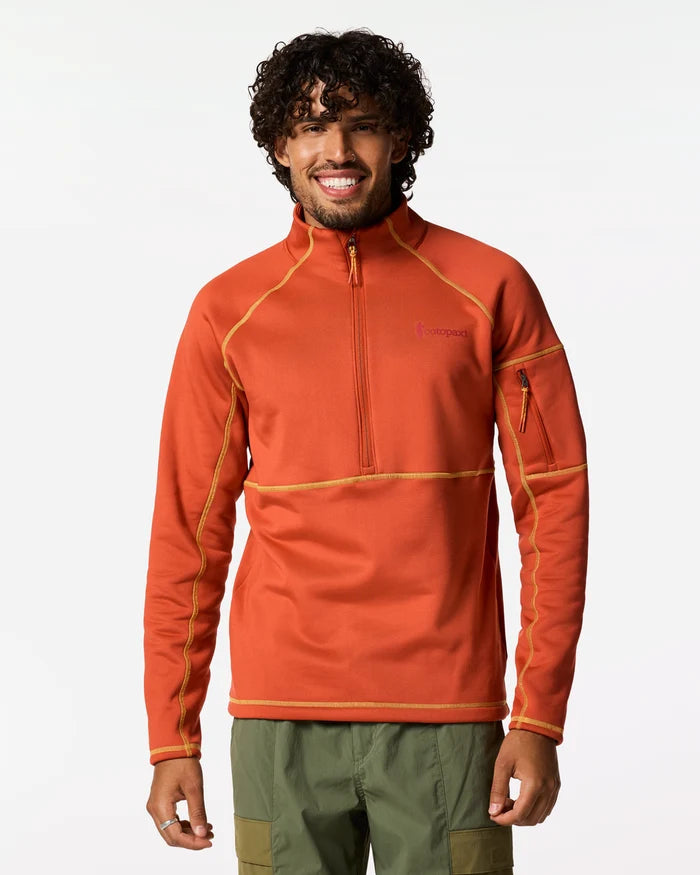 A men wears an orange coloured Tempa  1/4 zip fleece and green pants