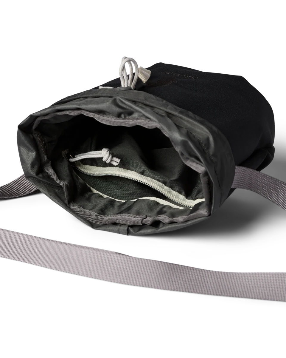 A black nylon sling bag shown open to reveal its interior, featuring a gray drawstring zipper pocket and a gray webbing strap, photographed on a clean white background.