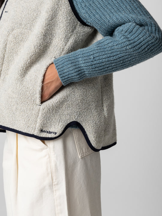 A close up of a womans hand in pocket of a wool vest