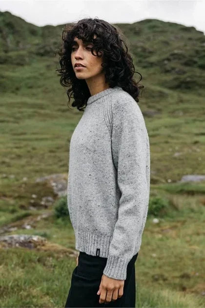 Woman stands in open field with grey wool sweater