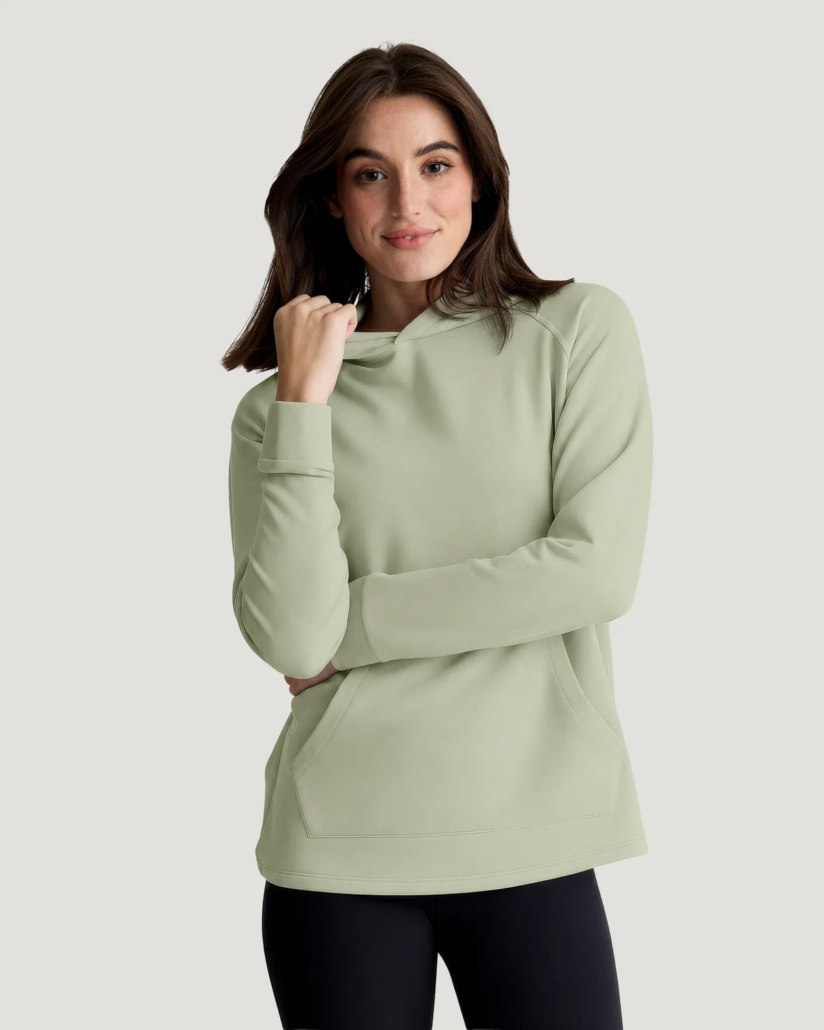 A woman in a studio wearing a tea green hoodie made of bamboo  