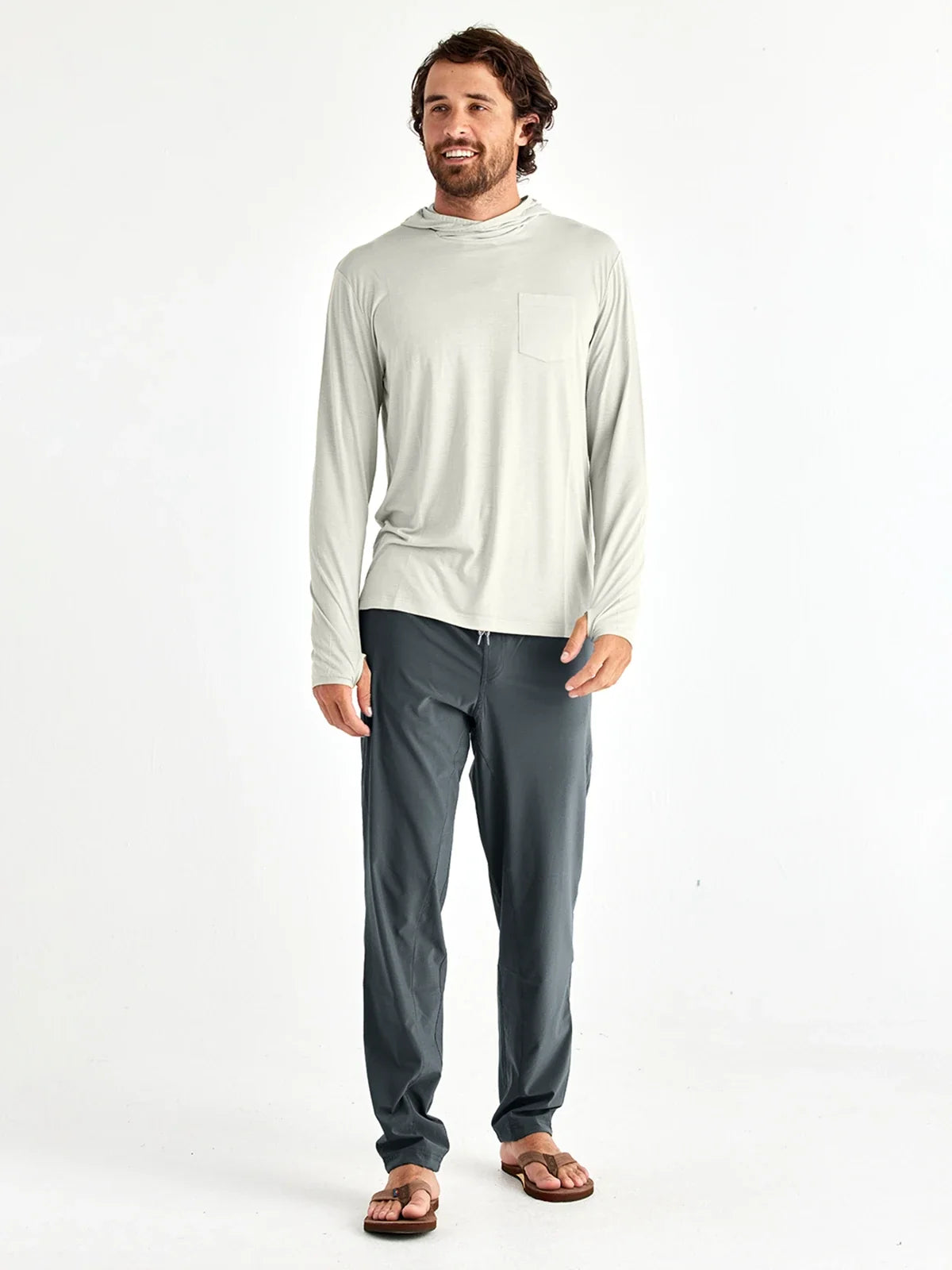 A man wearing a hoodie and upf breeze pants and sandals