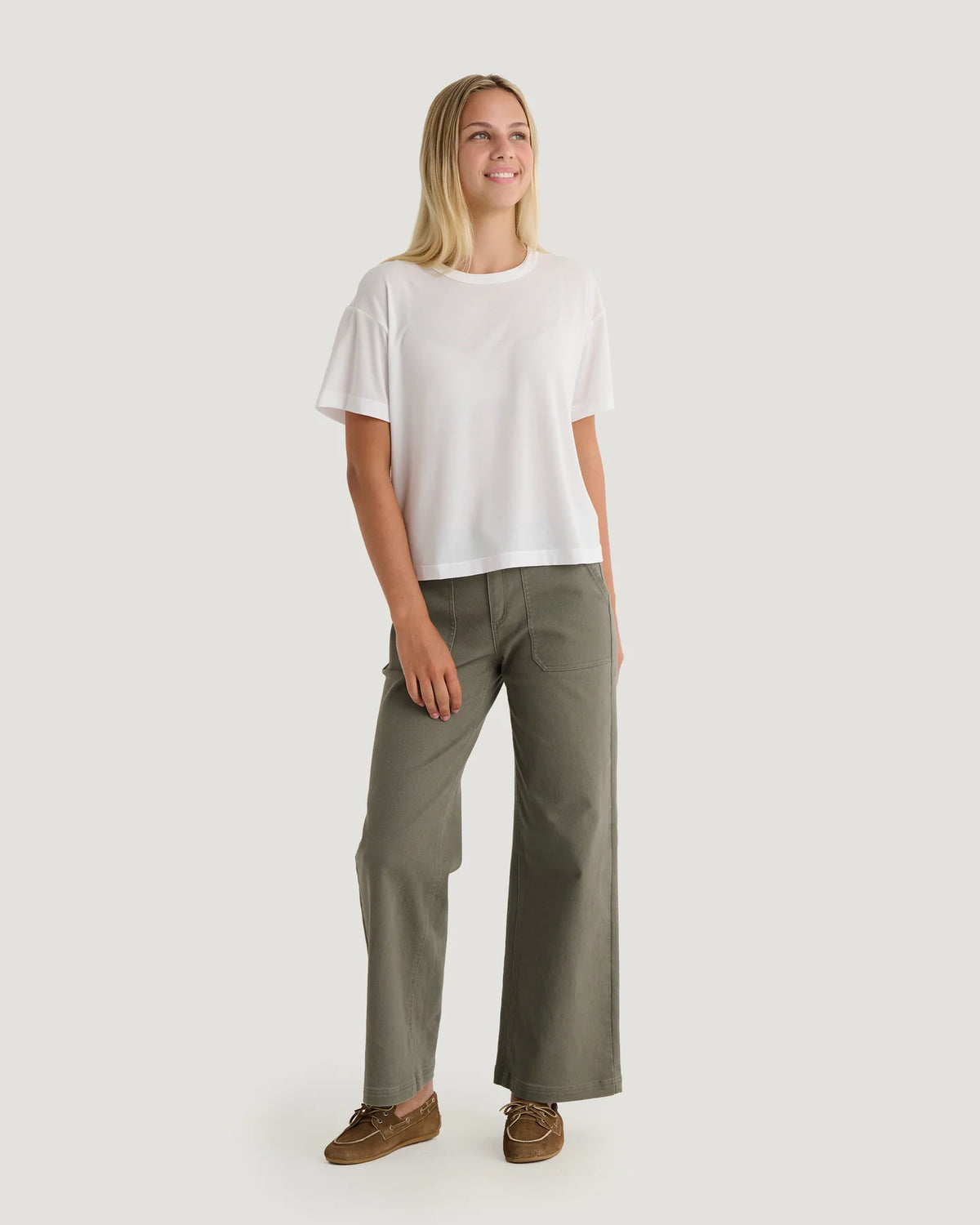 Woman wearing oiive pants with white shirt.
