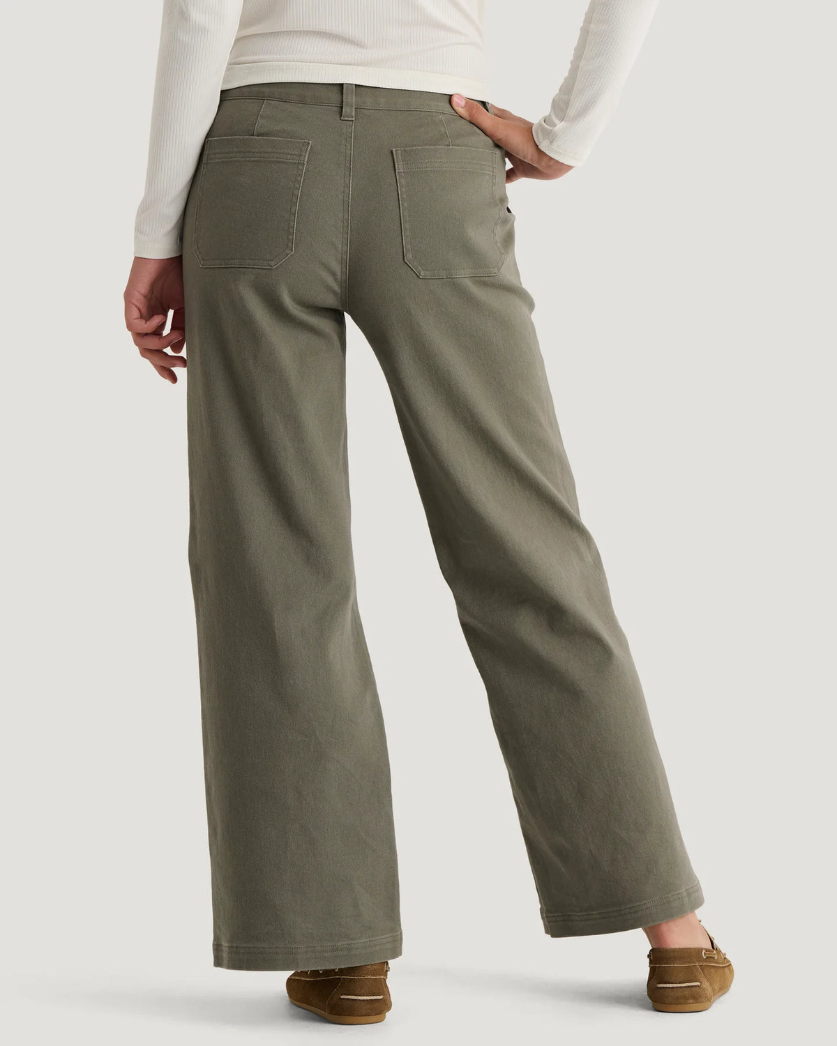 Woman standing wearing olive coloured wide leg pants with 2 back pockets