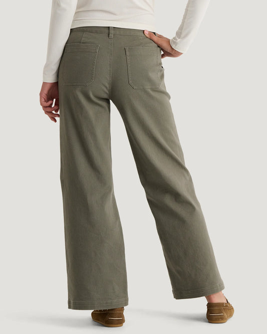 Woman standing wearing olive coloured wide leg pants with 2 back pockets