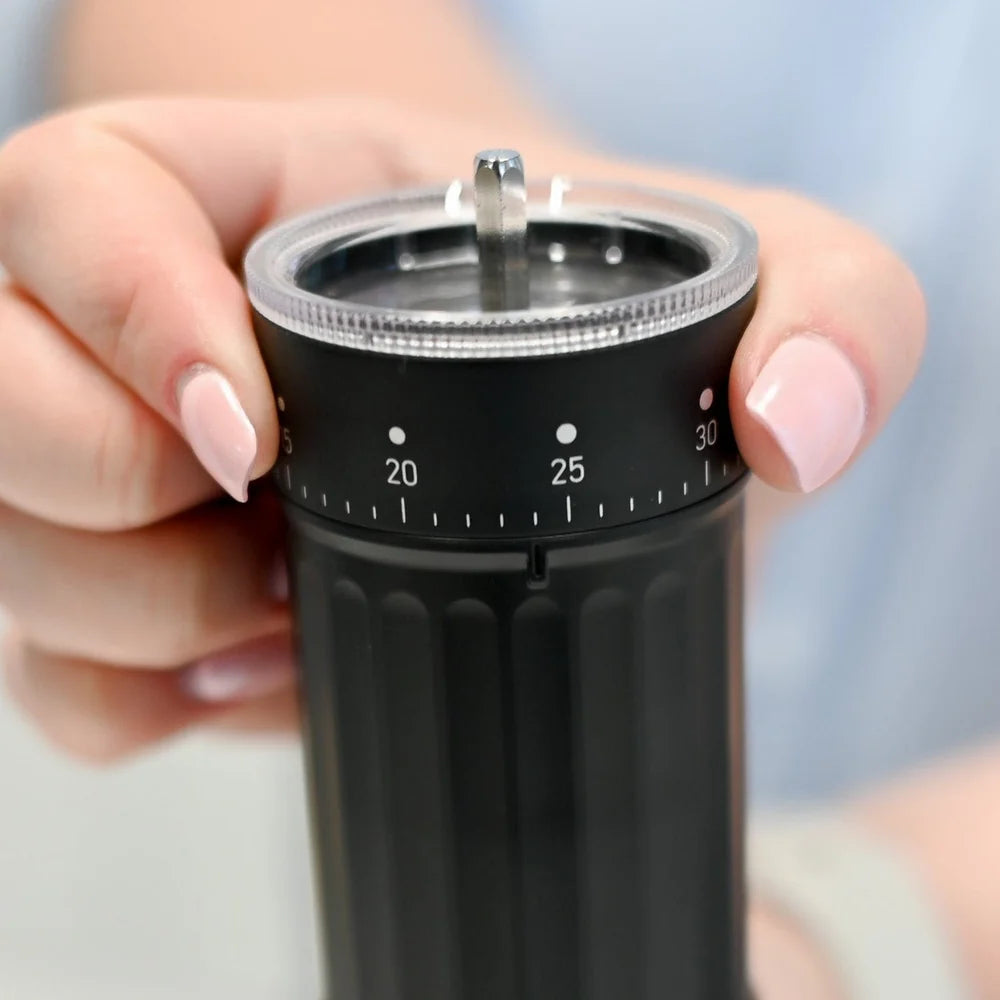 Grosche Tokio Manual Coffee Grinder Black kitchen timer with a hand holding it against a blurred background