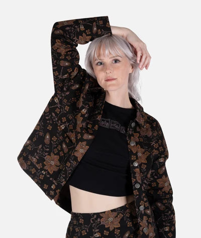 Jetty Supply Piper Jacket Person wearing a black floral jacket over a black top on a white background