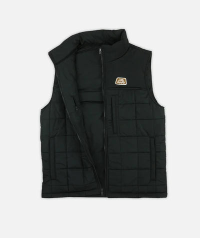 Jetty Terrace Vest A black quilted zip-up vest with a stand collar and a small rectangular logo patch on the left chest, displayed flat against a light gray background.