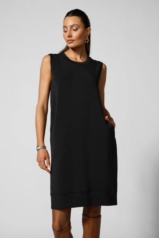 Woman wearing a black sleeveless dress against a plain background