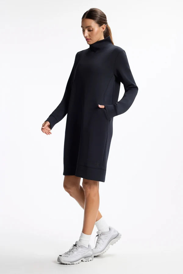A woman wears a comfy dress in black to be sold at CHANGE