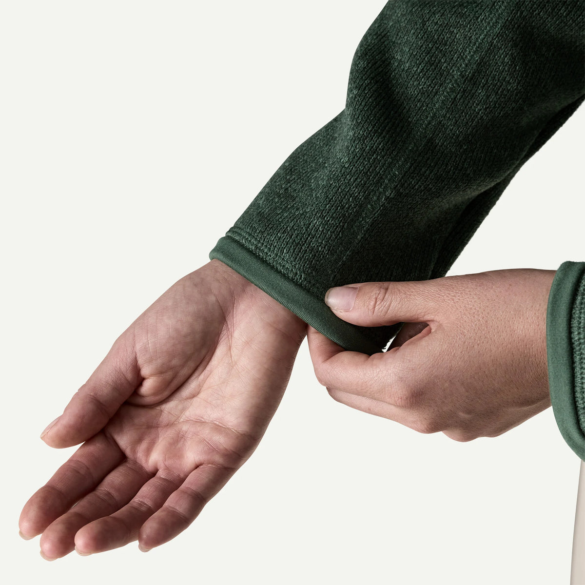 A close up a person showing the cuff on her green better sweater sleeve 