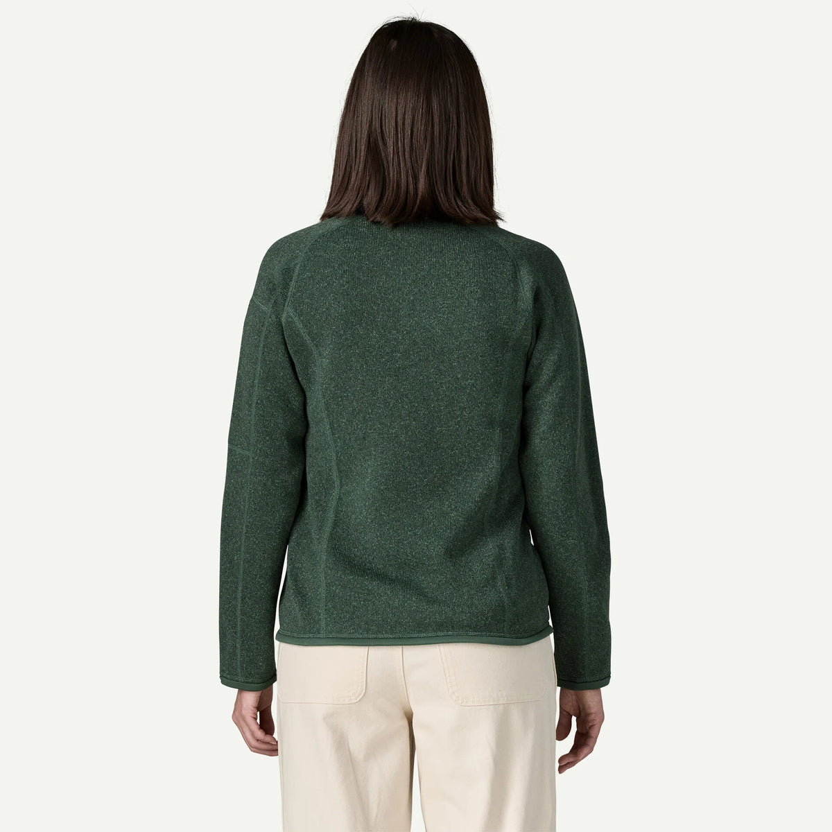 The back view of a woman wearing a green better sweater and cream pants