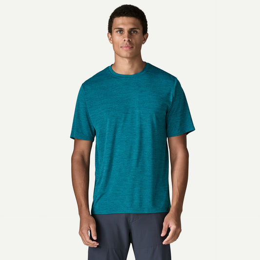 Patagonia Capilene Cool Daily Shirt Glacial Blue A man wearing a teal short-sleeve crewneck athletic t-shirt and dark gray pants, standing against a light off-white background.