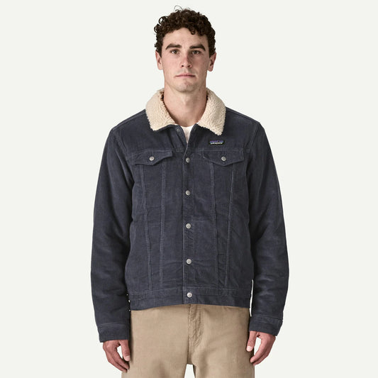 Patagonia Fleece Pile-Lined Trucker Jacket a man stands wearing a blue cord jacket with fleece collar.