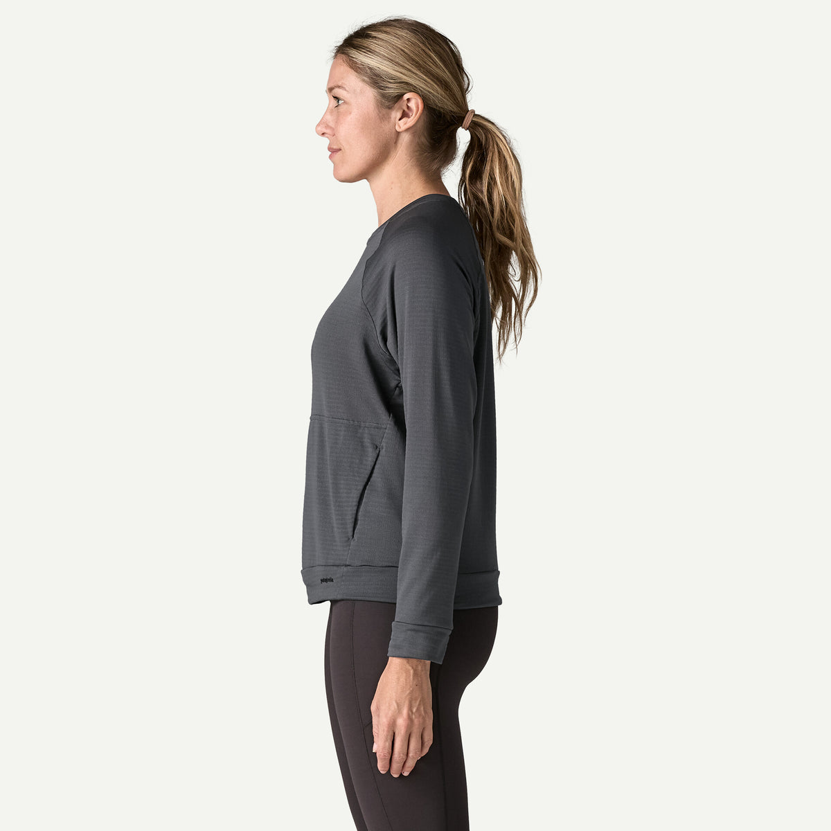 The side view of a woman wearing a black long sleeve top and black pants