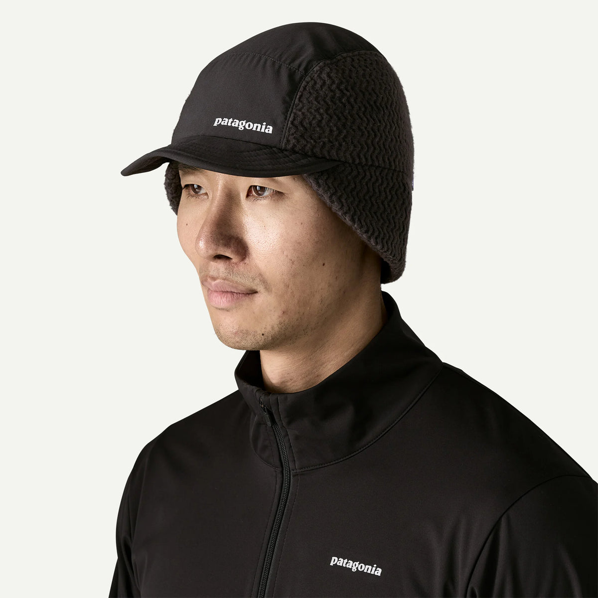 A man wears a black cap with ear flaps down 