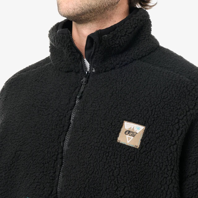 Close up of the chest of a person wearing a black fleece with a patch logo on the front