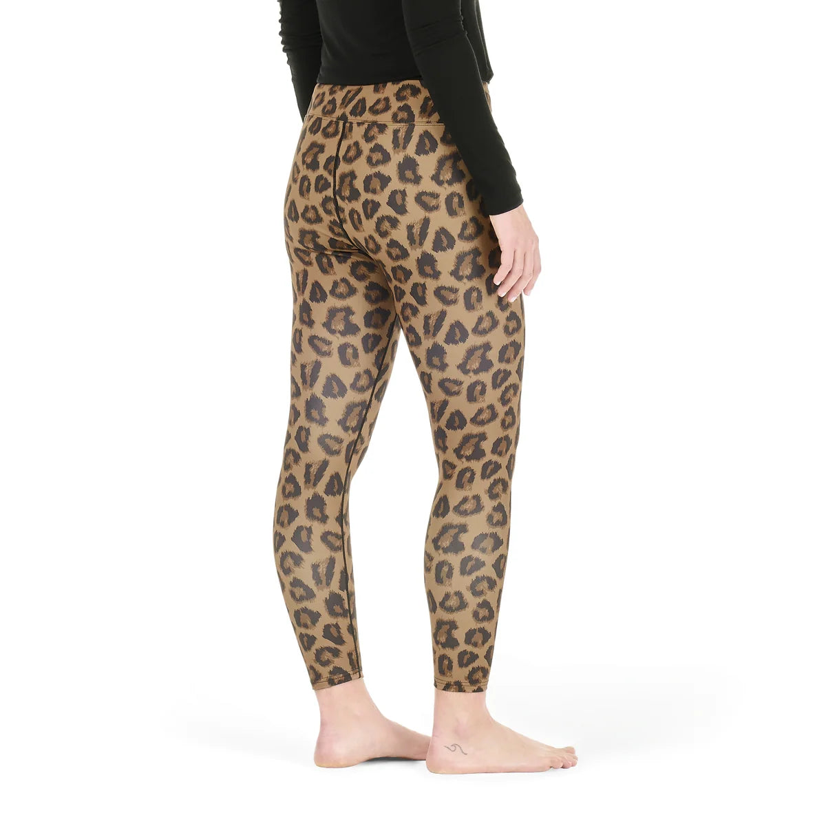 The back view of a woman standing in a white studio space wearing an animal print pair of tights and a black top.