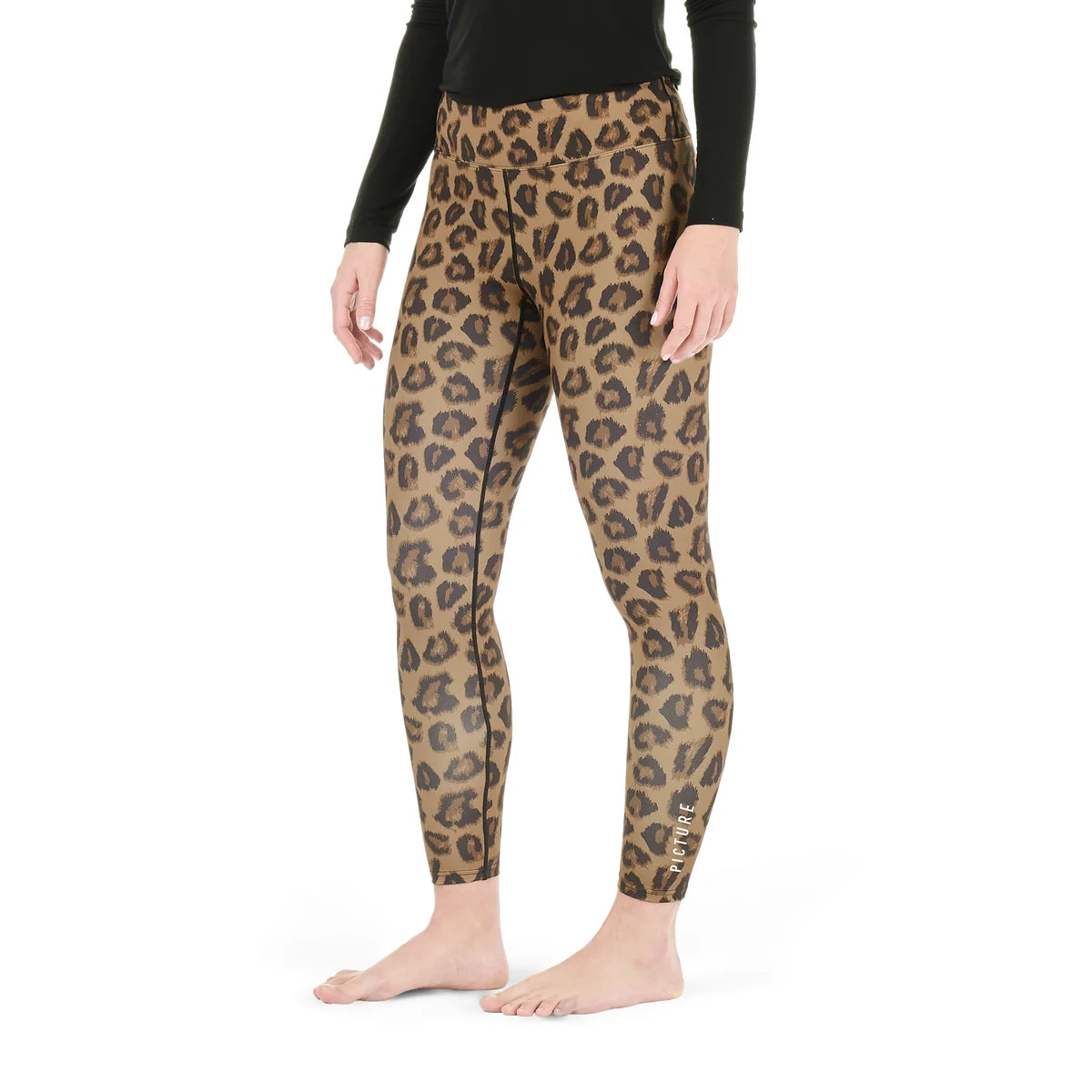 A woman stands in a white studio space wearing an animal print pair of tights and a black top.
