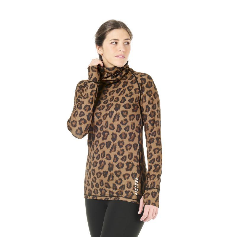 A woman stands in a white studio space wearing an animal print turtle neck base layer top and black tights