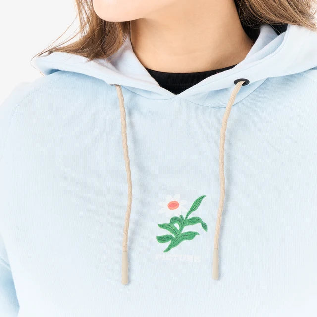 The close up of a woman wearing a blue hoodie with a floral embroidery on it