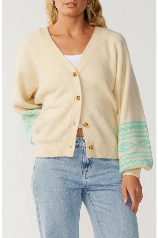Rip Curl Bossa Nova Jacquard Cardigan woman wearing a cream with green striped cardigan and blue jeans.