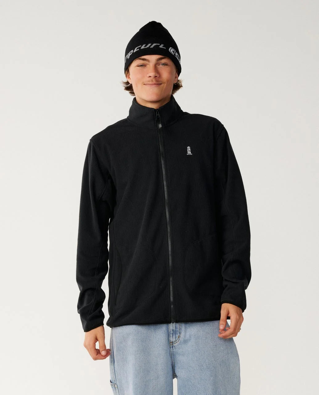 Person wearing a black jacket and beanie on a plain background