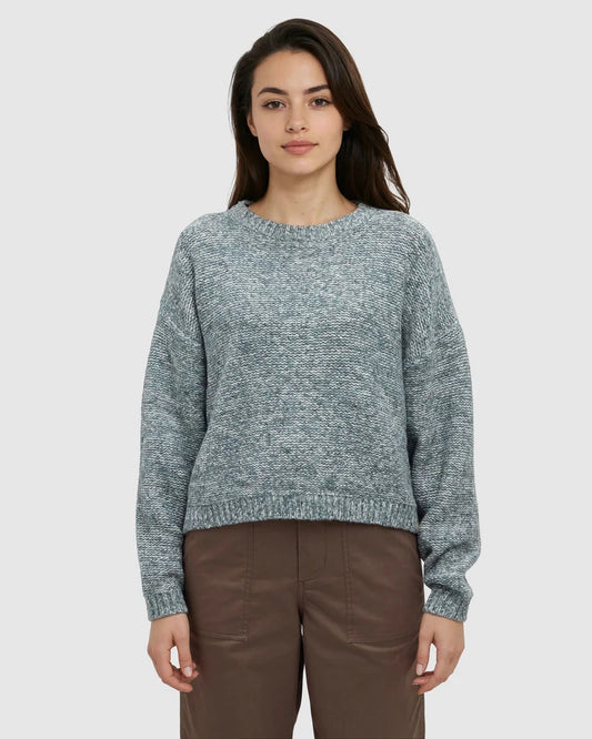 A woman wearing a green sweater and brown pants 