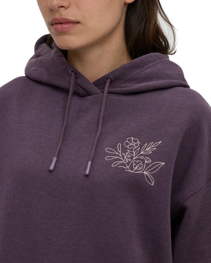 Tentree Field Foliage Hoodie A close-up of a person wearing a heathered purple pullover hoodie with a white embroidered floral design on the left chest and matching drawstrings.