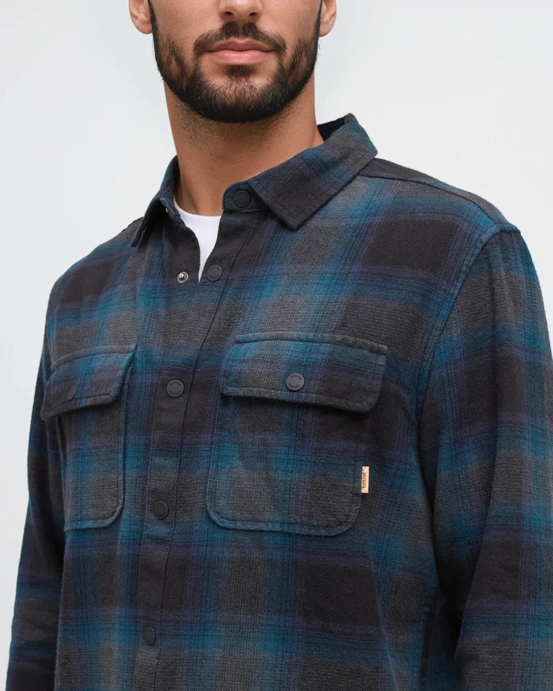 A medium close up of a man wearing a blue plaid shirt 