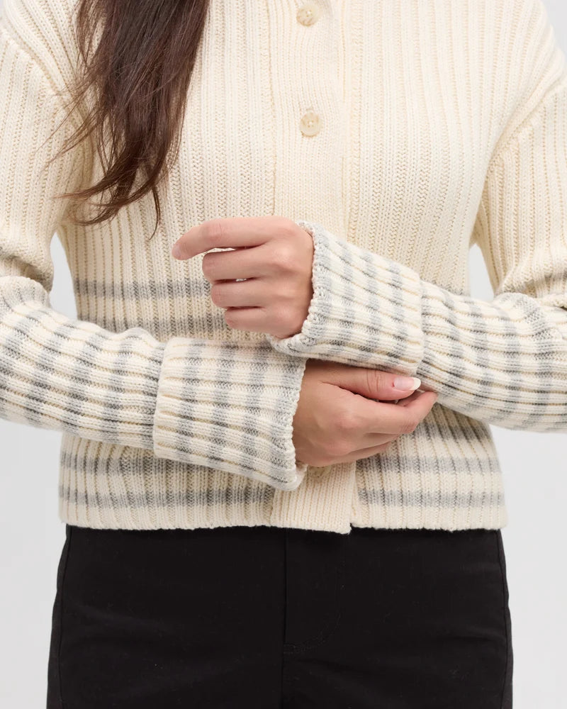 A close up of wide sleeves on a cardigan with a cream and grey stripes