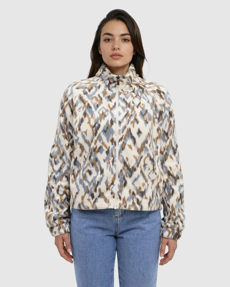 a woman standing wearing  a full zip multi coloured sweater with jeans
