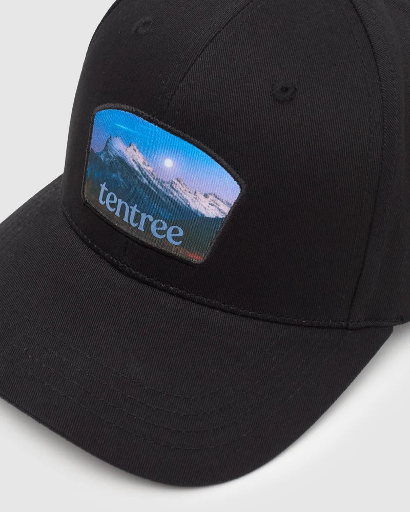 Tentree Parks Souvenir Elevation Hat A close-up of a black baseball cap featuring a rectangular patch on the front with a mountain landscape and the brand name 'tentree' in light blue text.