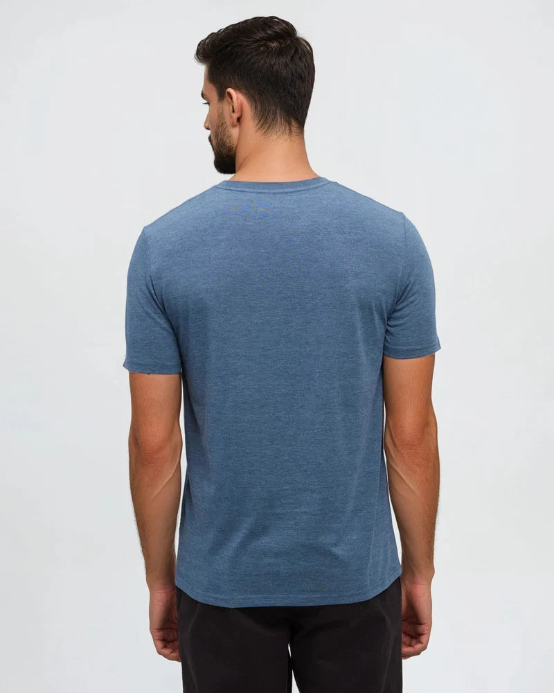 Tentree Protect Tee A man viewed from the back wearing a heathered blue crew-neck t-shirt and dark pants, set against a plain light gray studio background.