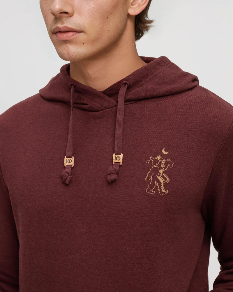 A man wearing a chestnut coloured hoodie with the image of a Sasquatch on the front.