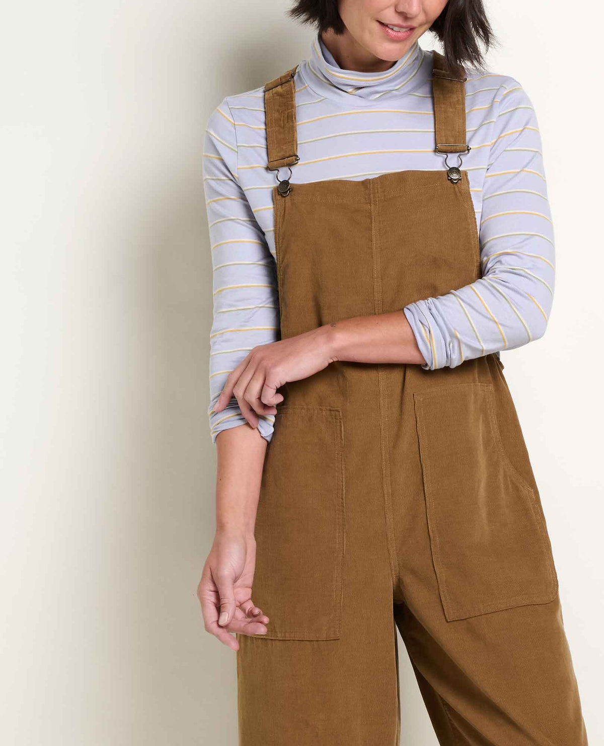 a person wearing corduroy brown overalls and a striped shirt