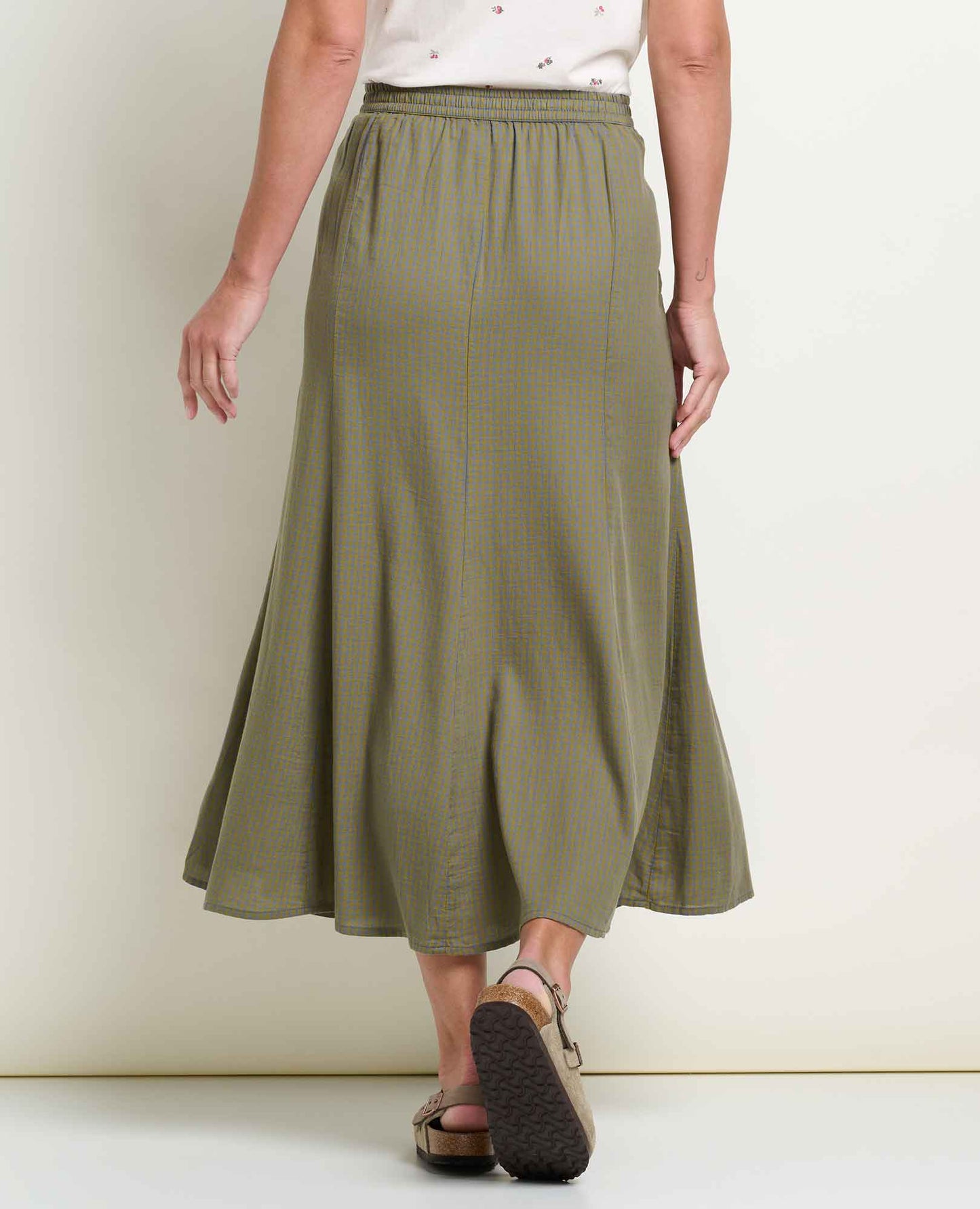 Toad and Co Manzana Organic Cotton Midi Skirt Green Moss Pattern A woman wearing an olive green and yellow gingham midi skirt with an elastic waistband, paired with brown leather sandals, shown from the waist down against a plain off-white background.