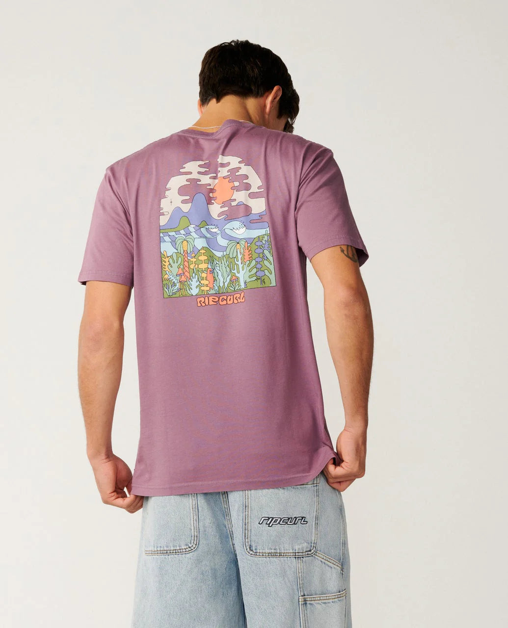 Person wearing a purple t-shirt with a colorful graphic on the back, standing against a plain background.